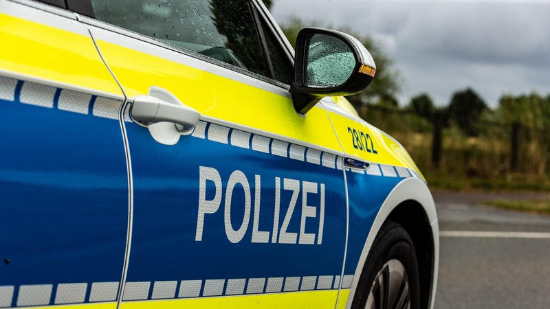 Ein Einsatzfahrzeug der Polizei steht mit Schriftzug auf einer Landstraße als Polizeiabsperrung.