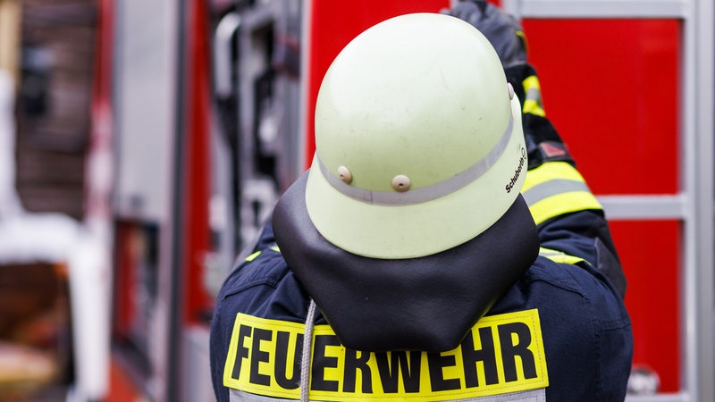 Ein Feuerwehrmann holt während einer Einsatzübung einer Freiwilligen Feuerwehr eine Leiter vom Dach eines Einsatzfahrzeugs.