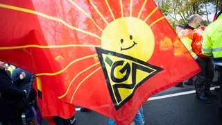 Eine Flagge der IG-Metall mit einer lachenden Sonne ist auf dem Bild zu sehen