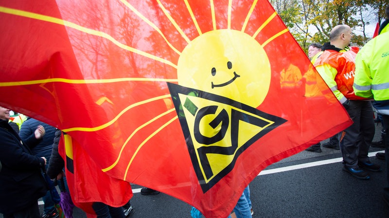 Eine Flagge der IG-Metall mit einer lachenden Sonne ist auf dem Bild zu sehen