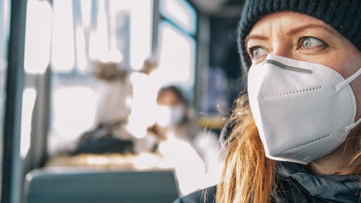 Eine Frau trägt in einer Straßenbahn einen Mund-Nasen-Schutz.