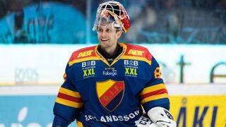 Der schwedische Eishockey-Torwart Niklas Svedberg strahlt auf dem Eis nach einer Partie.