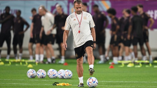Bundestrainer Hansi Flick rollt gedankenverloren ein paar Bälle zusammen am Rande des Trainings in Katar.