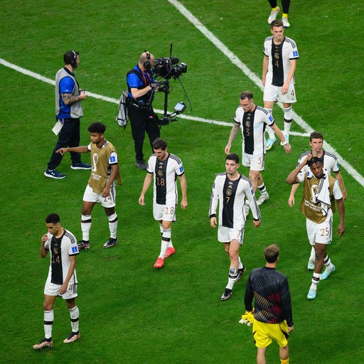 Enttäuschte deutsche Nationalspieler mit hängenden Köpfen verlassen den Rasen nach dem WM-Aus in Katar.