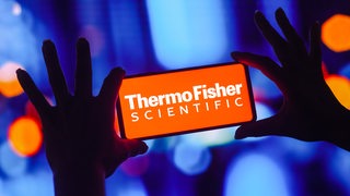 Der Schriftzug "Thermo Fisher Scientific" steht auf einem Handy-Display.