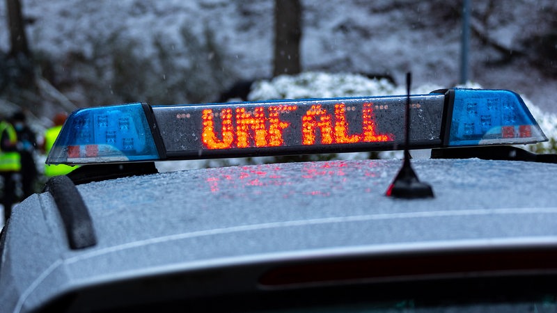 Polizeiwagen bei Schnee mit "Unfall"-Zeichen