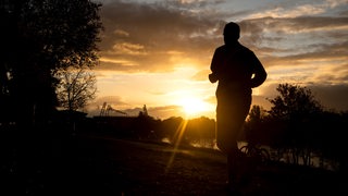Ein Jogger läuft am frühen Morgen über den Osterdeich.