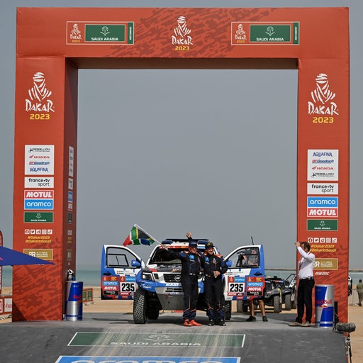 Die Rallye-Piloten Daniel Schröder und Ryan Bland posieren beim Start der Dakar-Rallye neben ihrem Auto.