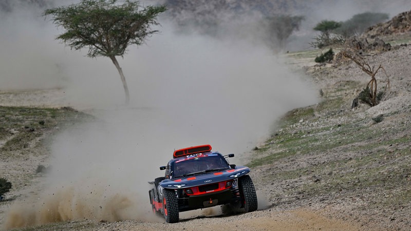 Rallye-Fahrer Carlos Sainz wirbelt auf der Strecke mit seinem Wagen jede Menge Sand auf.