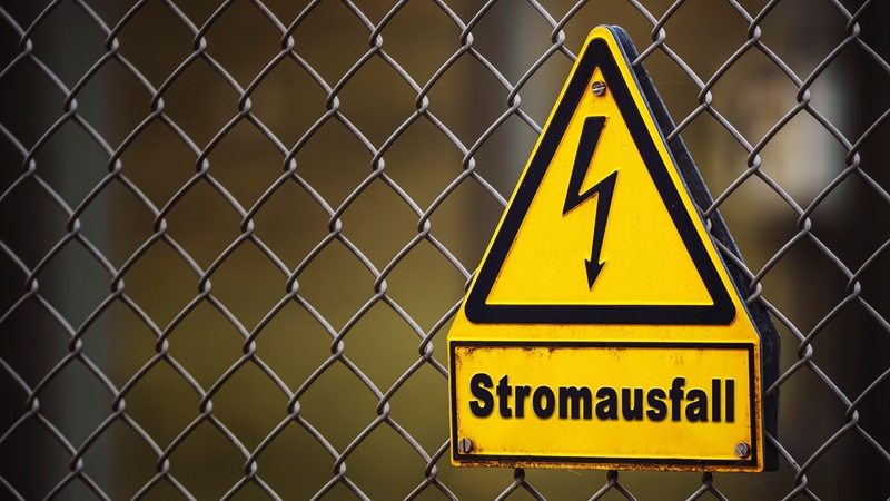 Schild an einem Zaun mit der Aufschrift: Stromausfall. Energiekrise FOTOMONTAGE 