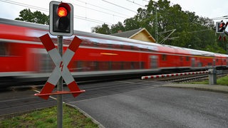 Ein Regionalexpress der Deutschen Bahn fährt schnell an einem Bahnübergang vorbei.