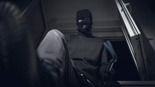 Maskierter Einbrecher hebelt mit Brecheisen ein Fenster auf und bricht bei Nacht in ein Haus ein.