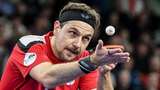 Tischtennis-Profi Timo Boll fokussiert konzentriert den hochgeworfenen Ball vor dem Aufschlag.