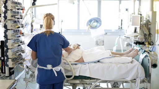 Eine Krankenschwester kümmert sich um einen Patienten auf der Intensivstation eines Krankenhauses.