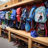 Sporttaschen und Schulranzen hängen an der Garderobe vor einem Klassenzimmer 