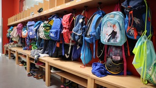 Sporttaschen und Schulranzen hängen an der Garderobe vor einem Klassenzimmer 