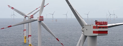 Zwei Techniker sind am 27.07.2017 auf einer Generatorgondel eines Windkraftrades (r) des Offshore-Windparks «Nordsee 1» in der Nordsee vor der ostfriesischen Insel Spiekeroog (Niedersachsen) mit der Inbetriebnahme beschäftigt.