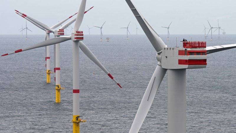 Zwei Techniker sind am 27.07.2017 auf einer Generatorgondel eines Windkraftrades (r) des Offshore-Windparks «Nordsee 1» in der Nordsee vor der ostfriesischen Insel Spiekeroog (Niedersachsen) mit der Inbetriebnahme beschäftigt.