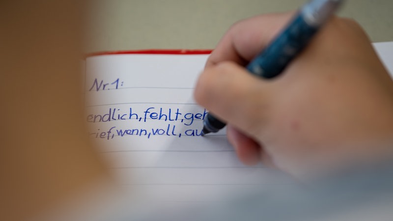 Ein Schüler schreibt Wörter in ihr Heft. 