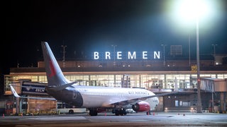 Ein Flugzeug steht nachts auf dem Rollfeld vom Flughafen Bremen. 
