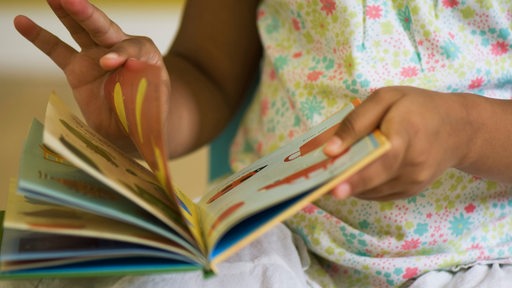 Kinderhände blättern durch ein Buch