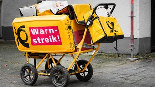 Auf einem Wagen eines Briefträgers steht die Aufschrift "Warnstreik!".
