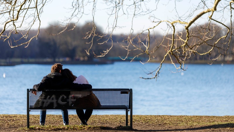 Mann und Frau sitzen auf Bank am See