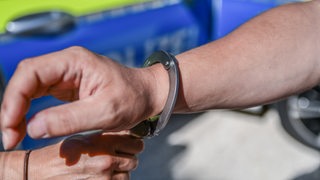 Eine Polizistin legt einer Person Handschellen an.