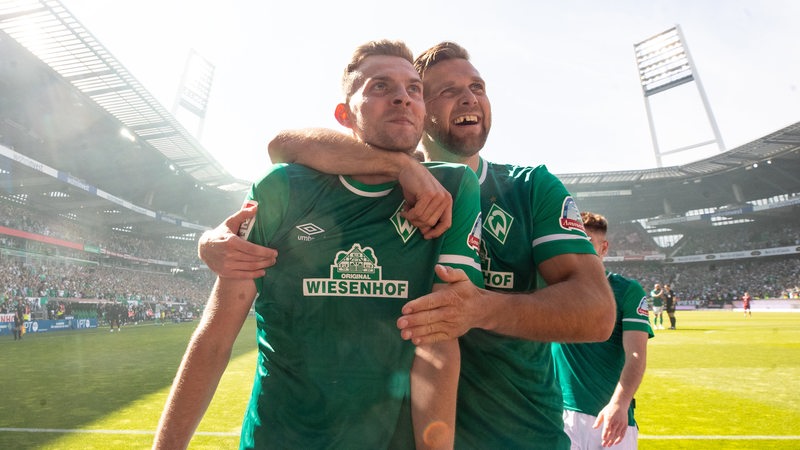 Werder-Spieler Duchsch und Füllkrug stehen an der Werbebande und freuen sich.