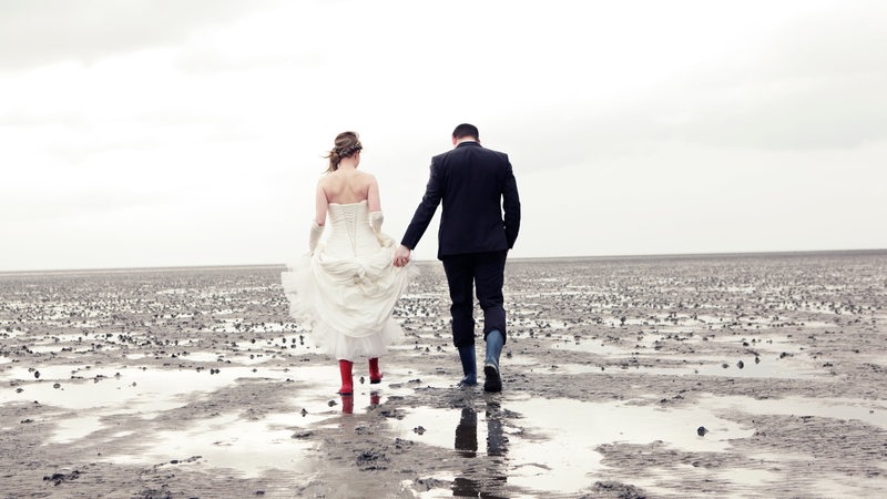 Ein Brautpaar spaziert durchs Wattenmeer