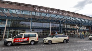 Das Terminalgebäude des Bremer Flughafens. Davor stehen Taxis.