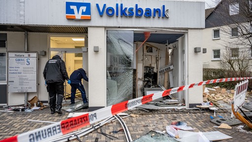 Mitarbeiter der Kriminaltechnik untersuchen eine schwer beschädigte Volksbank-Filiale nach der Sprengung eines Geldautomaten 