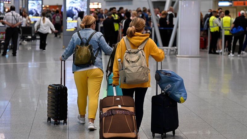 Passagiere gehen mit Gepäck durch durch ein Terminal am Flughafen