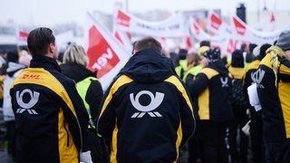 Post-Logo steht auf den Jacken der Demonstranten der Deutschen Post