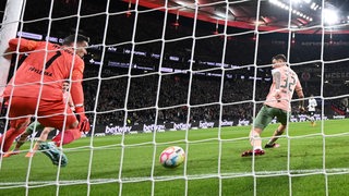 Blick durch das Tornetz, als Werder-Kapitän Marco Friedl ein Eigentor gegen Keeper Jiri Pavlenka unterläuft.