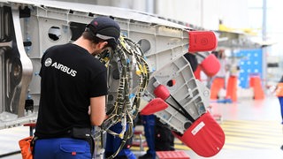 Ein Mitarbeiter von Airbus arbeitet am Flügel eines A350