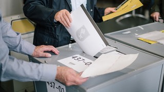 Ein Mann wirft seinen Stimmzettel für die Bürgerschaftswahl in eine Wahlurne