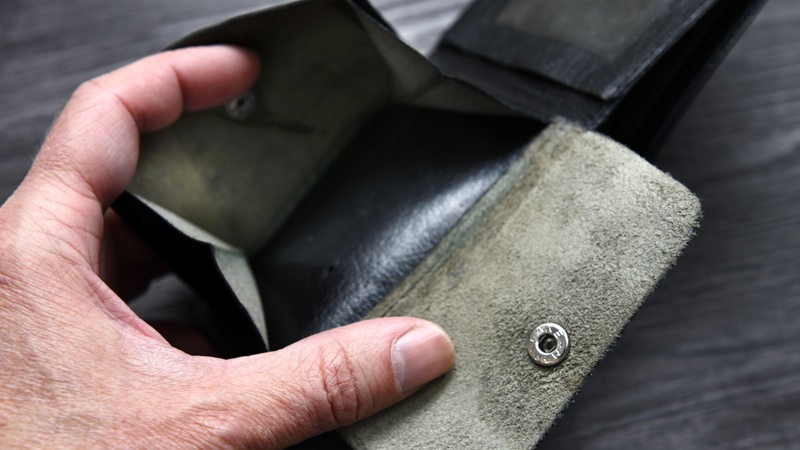 Eine Hand öffnet ein leeres Leder-Portemonnaie.