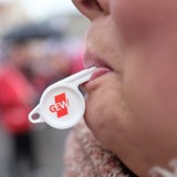 Eine Trillerpfeife steckt in einem Mund.