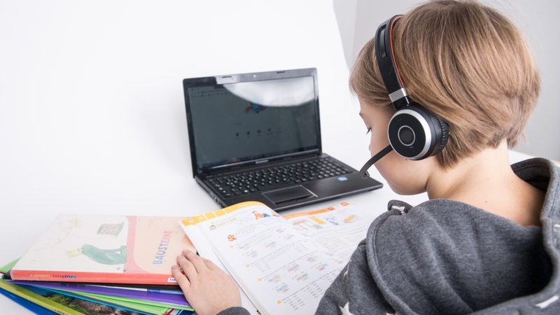 Ein Kind nimmt zu Hause mit Laptop am Distanzunterricht teil.