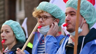 Streikende Pflegerinnen und Pfleger protestieren mit Trillerpfeifen und Fahnen.