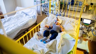 Ein achteinhalb Monate altes Kind liegt in einem Bett in einem Krankenhaus.