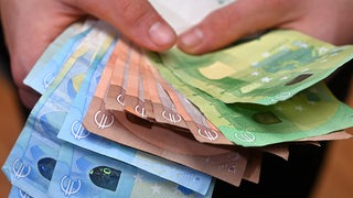 Hände halten viele Euro-Banknoten