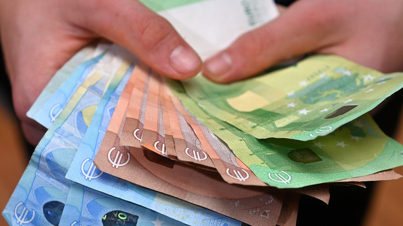 Hände halten viele Euro-Banknoten