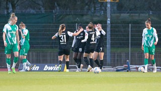 Enttäuschte Werder-Fußballerinnen schauen den Gegnerinnen aus Frankfurt beim Torjubel zu.