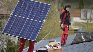Arbeiter installieren Solarmodule auf einem Hausdach