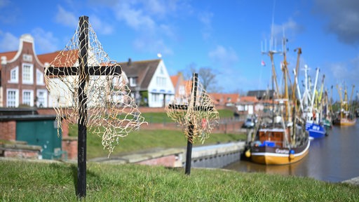 Schwarze Kreuze mit Netzen stehen am Hafen