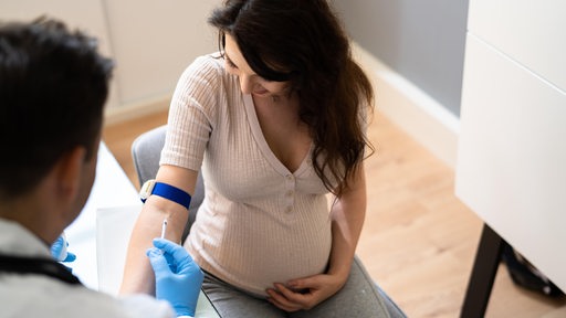 Doktor nimmt Blut bei Schwangerer ab