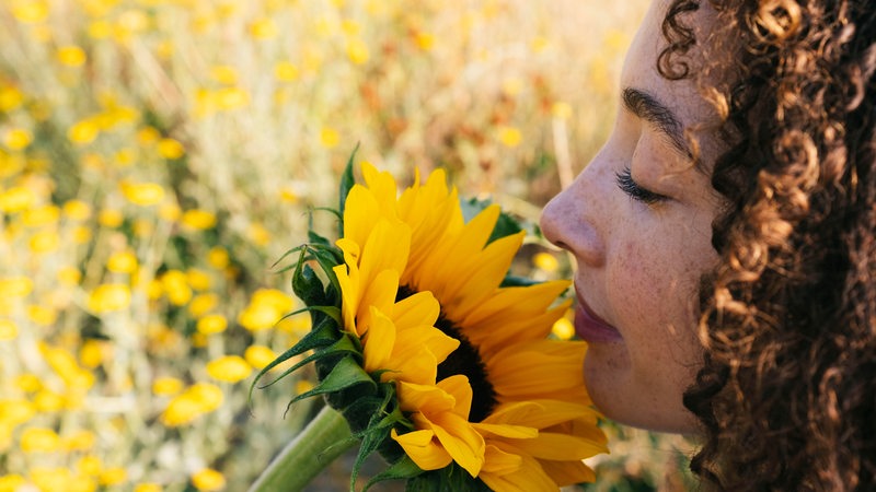Eine Frau riecht an einer Sonnenblume