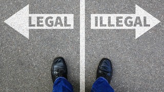 Zwei Füße auf einer Straße, links steht "legal", rechts "illegal"